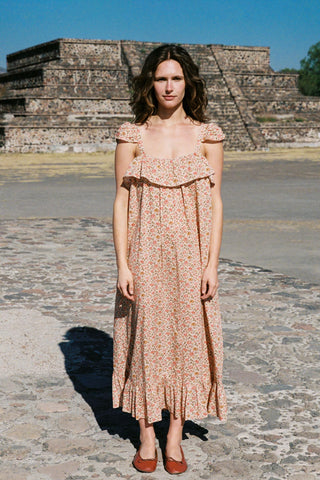 Woman in a floral dress standing in front of ancient ruins