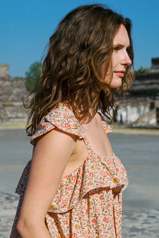 Woman in a floral dress standing outdoors with historical architecture in the background