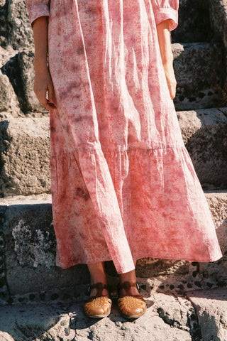 Person wearing a pink dress standing on stone steps.