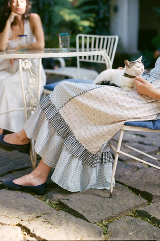 Person sitting outdoors with a cat on their lap, wearing a patterned skirt.
