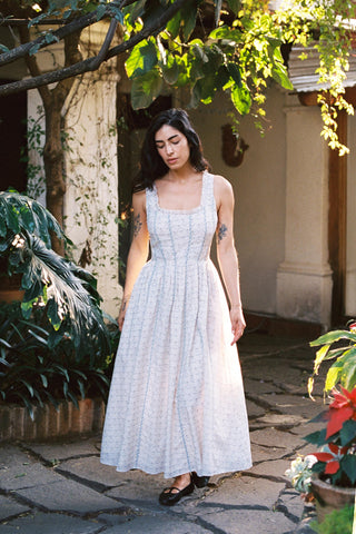 Woman in a light blue dress standing outdoors under a tree