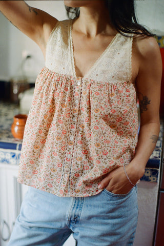 Person wearing a floral sleeveless top and blue jeans in an indoor setting.