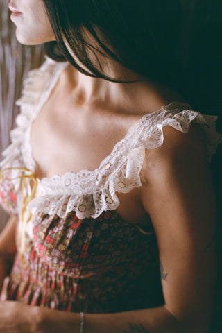 Close-up of a person wearing a lace-trimmed top with a blurred background