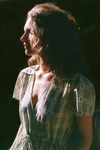 Woman wearing a patterned dress against a dark background