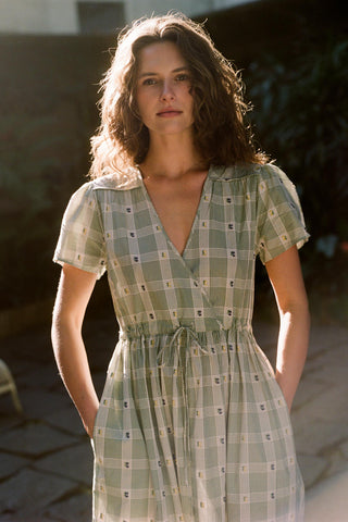 Woman wearing a green checkered dress standing outdoors.