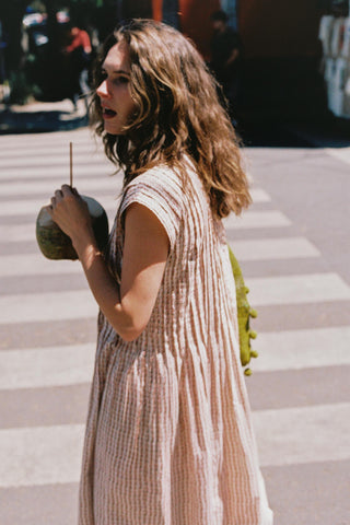 Woman holding a green bag and coconut walking over a crosswalk