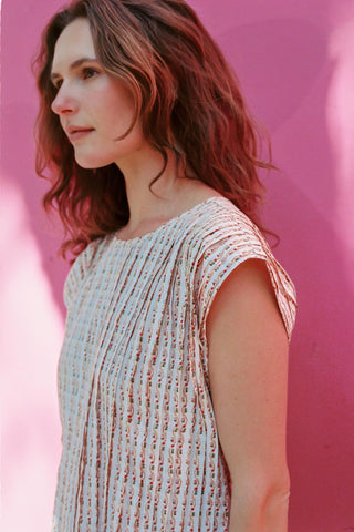 Woman wearing a patterned dress against a pink background