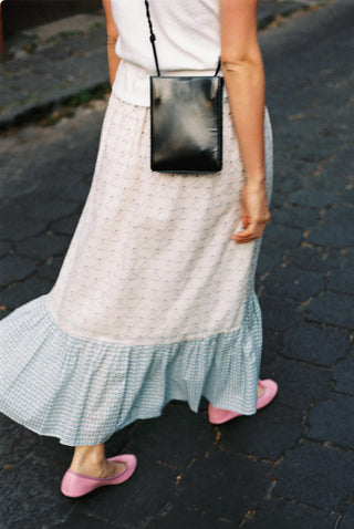 Person wearing a long, light-colored dress with a ruffled hem on a stone pavement.