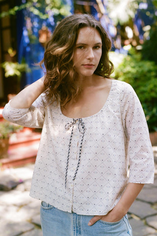 Woman wearing a light blouse with a garden background