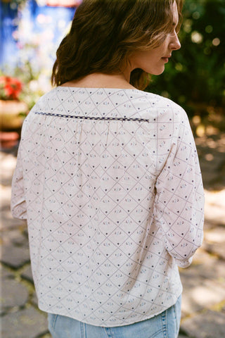 Woman wearing a light white blouse with a subtle pattern in an outdoor setting