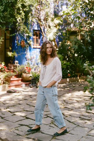 Woman standing in a garden with a colorful building in the background