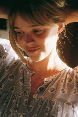 Woman with blonde hair and a patterned dress in a softly lit setting