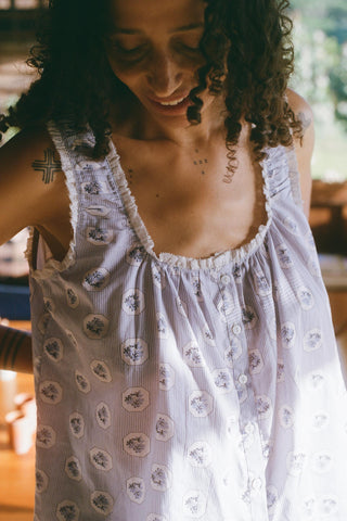 Woman wearing a white floral dress with a blurred natural background