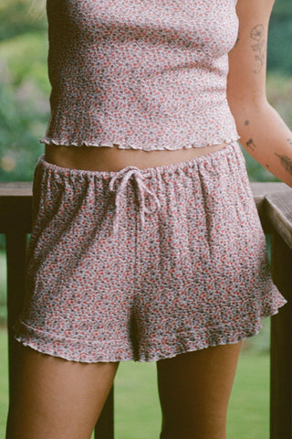 Person wearing a floral pajama set with a blurred green background
