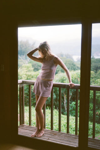 Woman standing on a balcony overlooking a lush green landscape