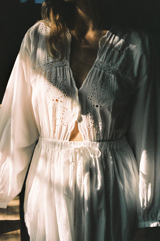 Close-up of a person wearing a white lace dress with a blurred background