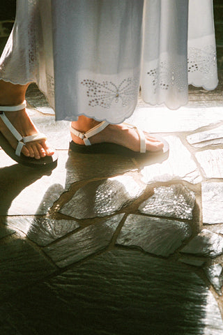 White sandals on a stone floor with sunlight casting shadows