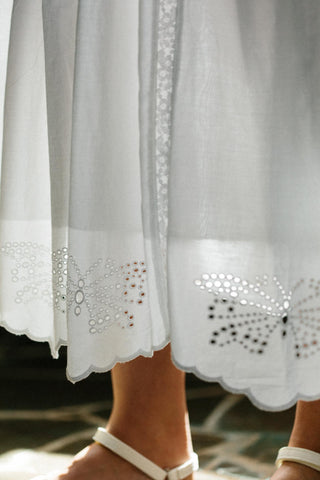 Close-up of a white skirt with intricate cut-out patterns and embellishments.
