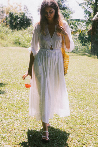 Woman in a white dress walking outdoors on a sunny day