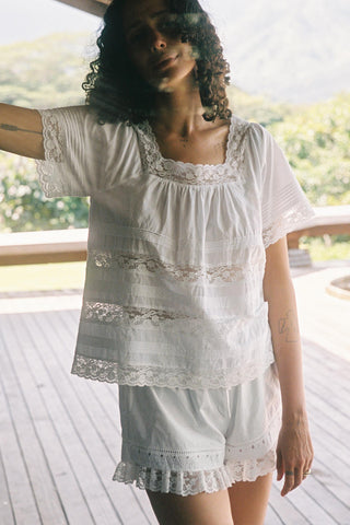 Woman wearing a white lace outfit with a blurred natural background