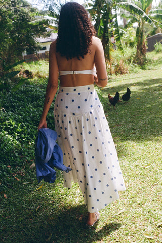 Woman in a polka dot dress walking outdoors with chickens in the background