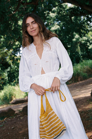 Woman in a white dress holding a yellow bag outdoors