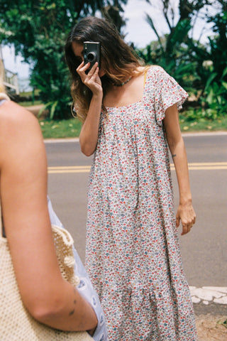Woman in a floral dress standing on a road with greenery in the background