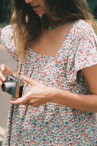 Person holding a camera wearing a floral dress