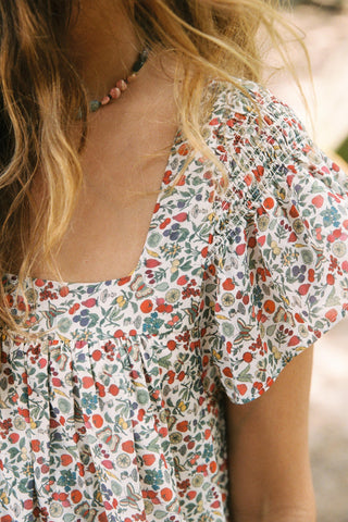 Floral blouse with ruffled sleeves worn by a person, blurred background