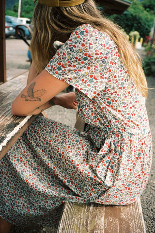 Woman in a floral dress sitting on a bench outdoors