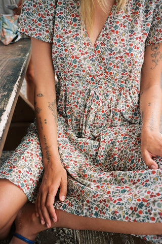 Person wearing a floral dress sitting on a bench.