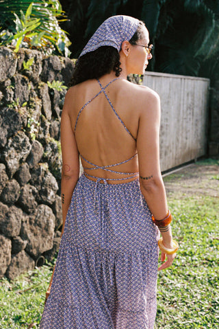 Woman in a floral dress standing outdoors near a stone wall.