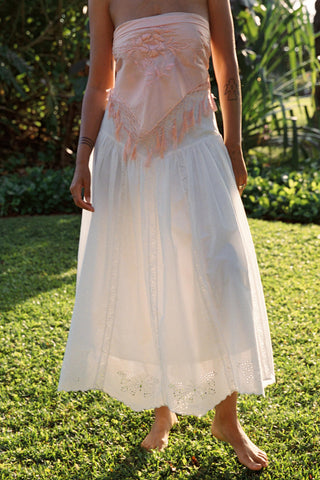 Person wearing a white lace skirt with a pink top in a garden setting