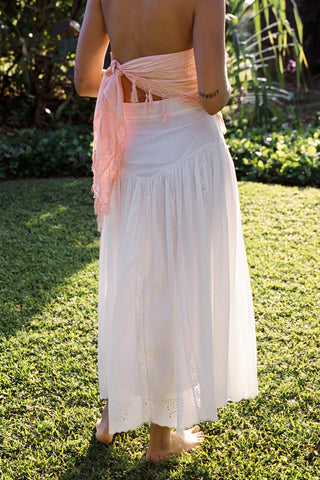 Person wearing a white skirt with a pink top in a garden setting