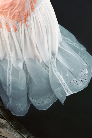 Close-up of a white lace skirt with pink top on a dark background