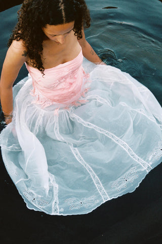 Young girl in a pink top and white skirt sitting in water