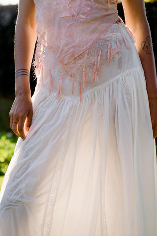 Person wearing a pink top and white skirt with a blurred background