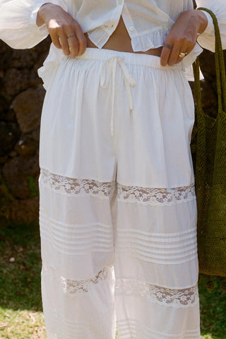 White lace-trimmed pants worn by a person outdoors.