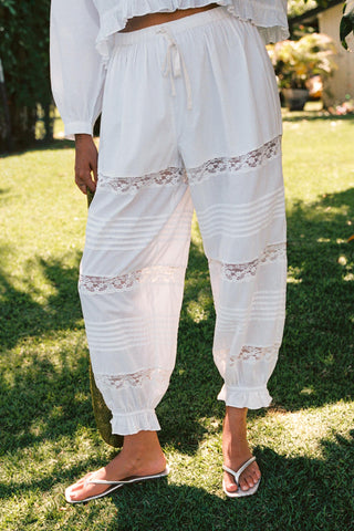 Person wearing white lace-trimmed pants standing on grass