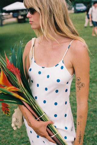 Woman in a polka dot dress holding flowers outdoors