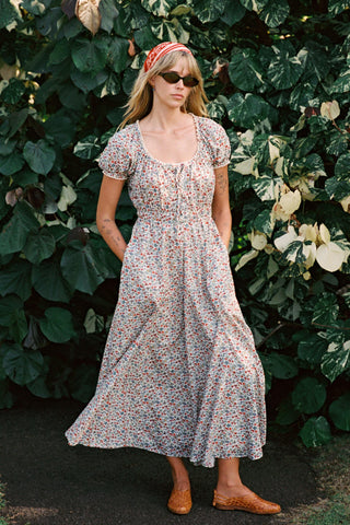 Woman in a floral dress standing in front of a leafy green background