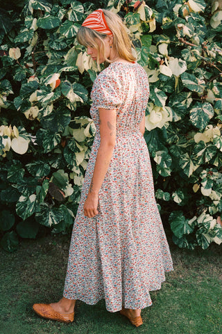 Woman in a floral dress standing in front of a leafy green background