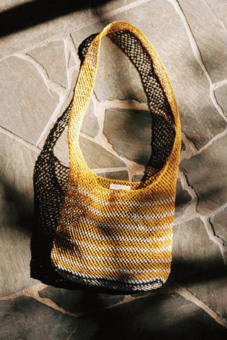 Yellow and black woven bag on a stone surface