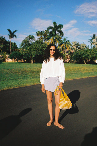Woman standing on a driveway with palm trees in the background