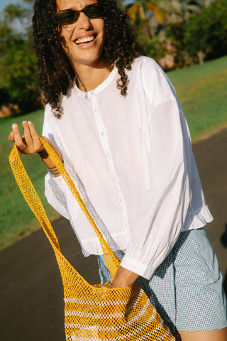 Woman holding a yellow and white striped bag outdoors