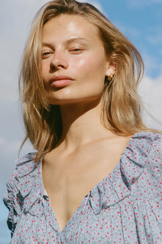 Woman wearing a light blue floral patterned dress with a clear blue sky background