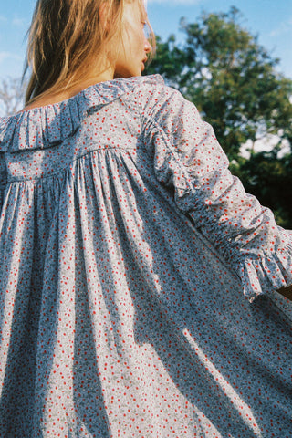 Person wearing a light blue floral patterned dress with trees in the background