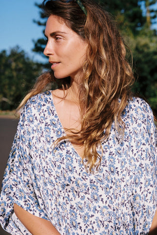 Woman wearing a floral blouse with a blurred natural background