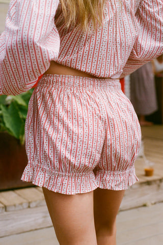 Person wearing a red and white patterned outfit with a blurred background