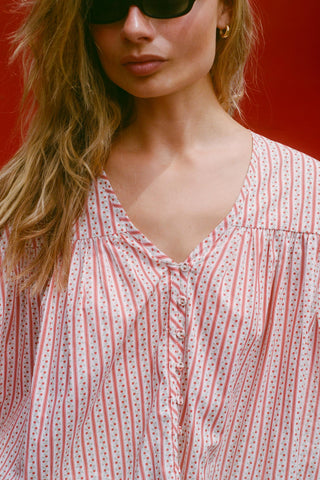 Woman wearing a red and white patterned blouse against a red background